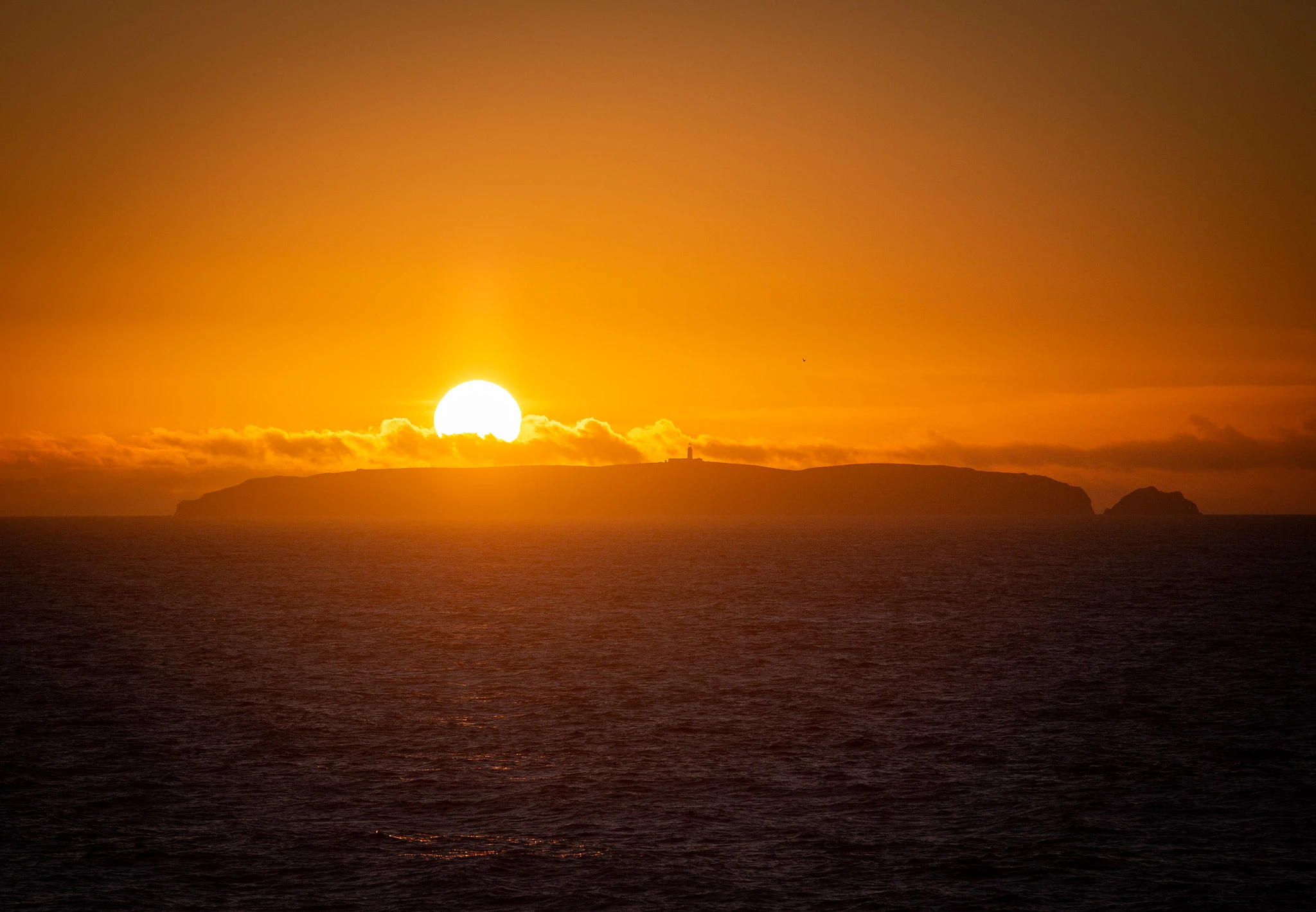 The sun sets directly behind the Berlengas Islands, its enormous white disc hovering above the island silhouette, the sky and sea turned to deep burnt orange and the horizon on fire.